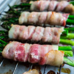 bacon wrapped around asparagus spears on a baking sheet