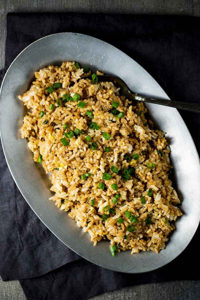 fried rice on a plate with a spoon and green onions