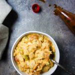 creamy tomatoes and onions in a bowl with a bottle of spilled hot sauce in the background
