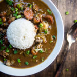 lousiana seafood gumbo with okra, seafood and sausage in roux in a bowl with rice