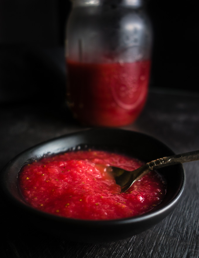 strawberry sauce in a black dish with jar in background