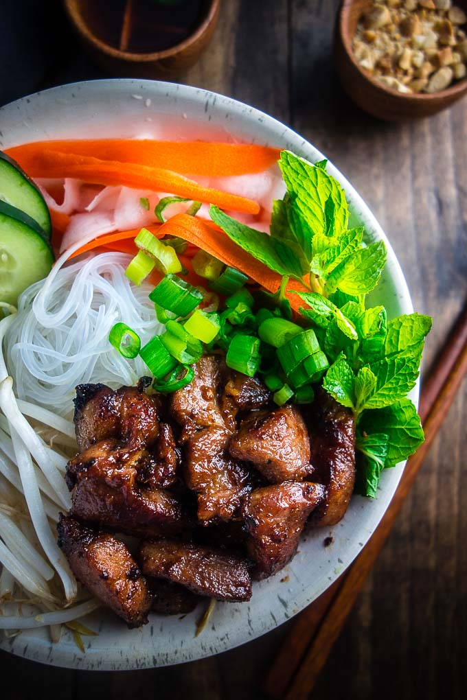 vietnamese pork in a bowl with noodles fresh herbs and carrots