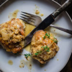 chicken thighs in white wine mustard sauce on a plate with fork and kmife