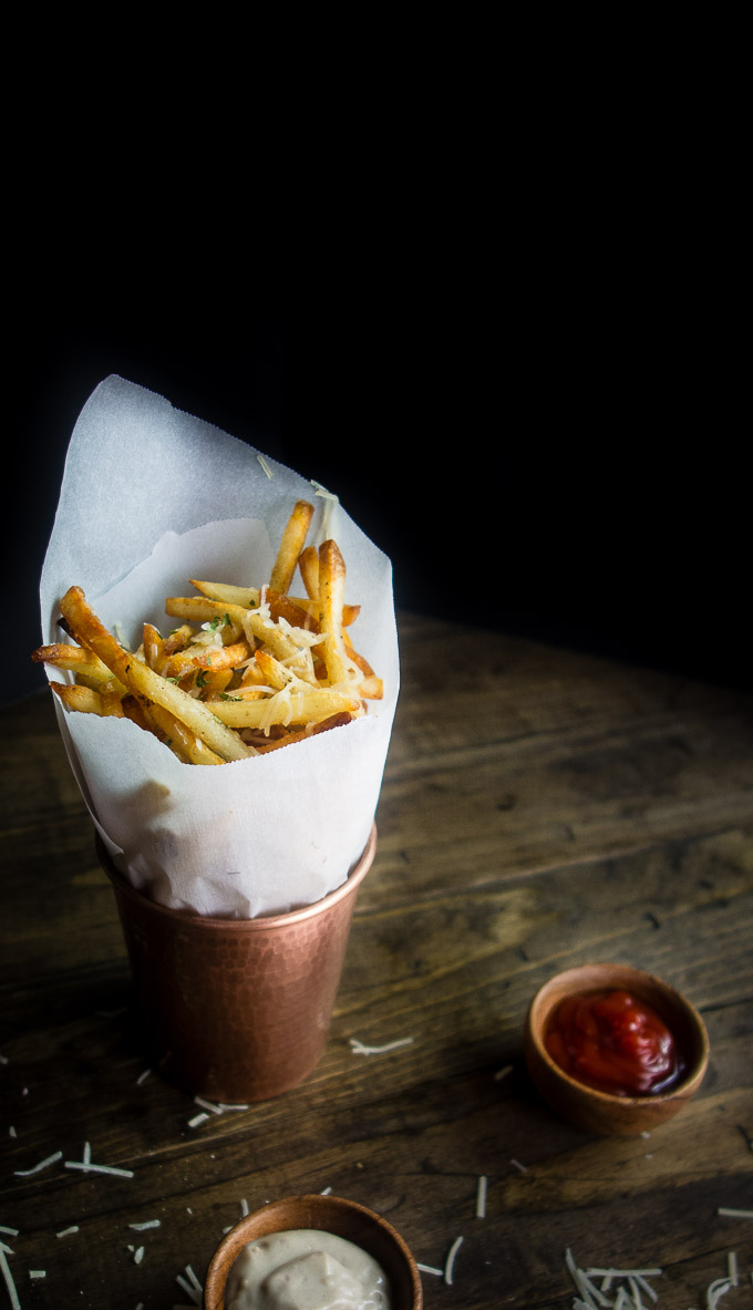 french fries in a cup with parchment paper with ketchup and truffle mayo on the side