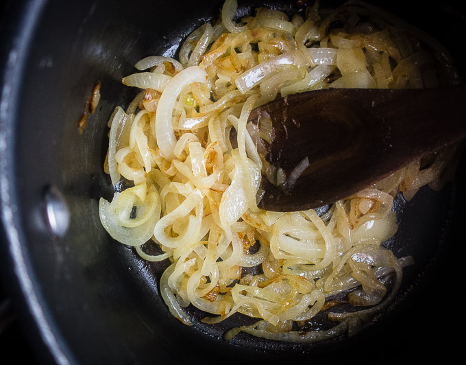 caramelized onions in a sauce pan with a wooden spoon