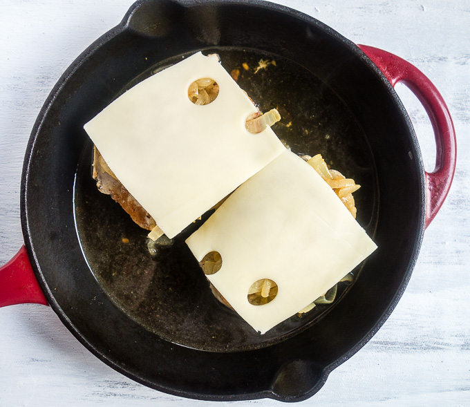 pork chops covered with swiss cheese in a skillet