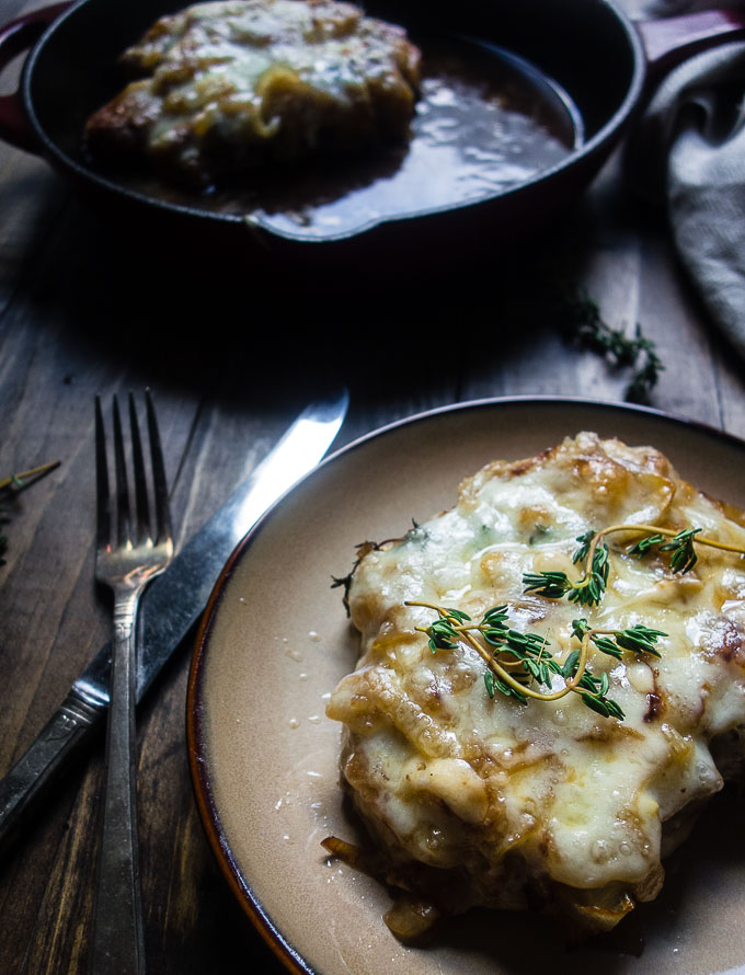 pork chop smothered in cheese with skillet in background, french onion smothered pork chops