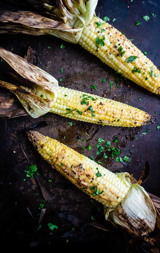 grilled corn on the cob on a platter with seasoning