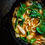 soup in a pot with noodles, spinach and thick broth