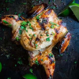grilled cornish game hens covered in sauce and cilantro with lime