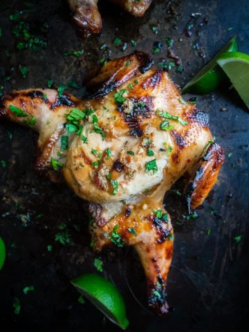 grilled cornish game hens covered in sauce and cilantro with lime