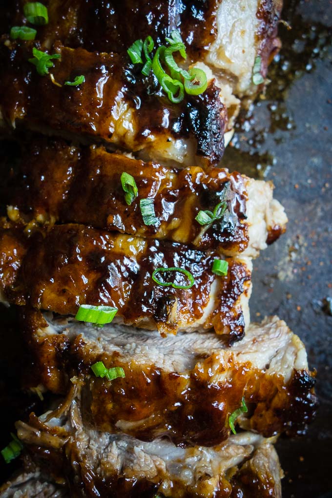 close up of ribs on a baking sheet with sauce and green onions