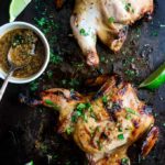 2 grilled cornish game hens covered in sauce and cilantro with lime
