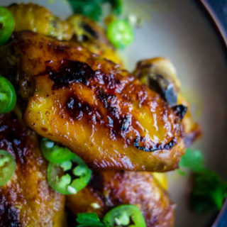 close up of caramelized chicken wings with chilies and cilantro