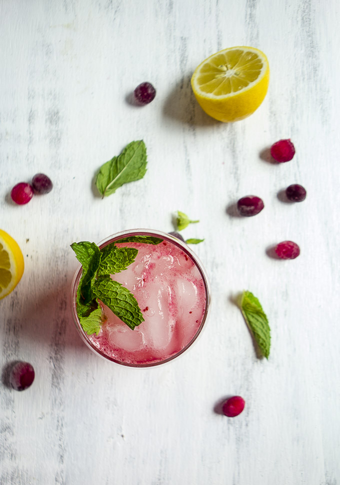 glass of sparkling cranberry lemonade garnished with mint, cranberries and lemon slices