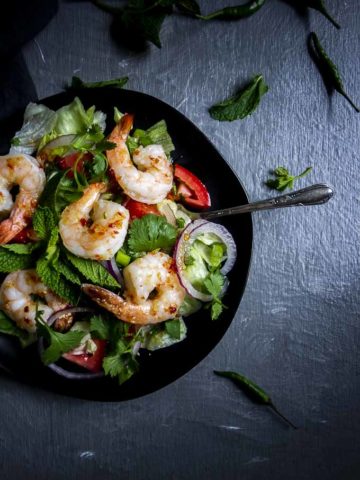 salad with shrimp on top in a bowl with chili dressing
