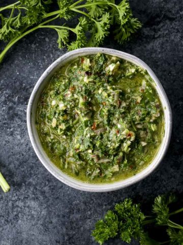 green herbs and sauce in a bowl garnished with parsley on the sides
