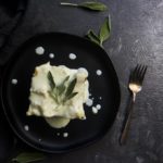 piece of bechamel lasagna on a plate with fresh sage