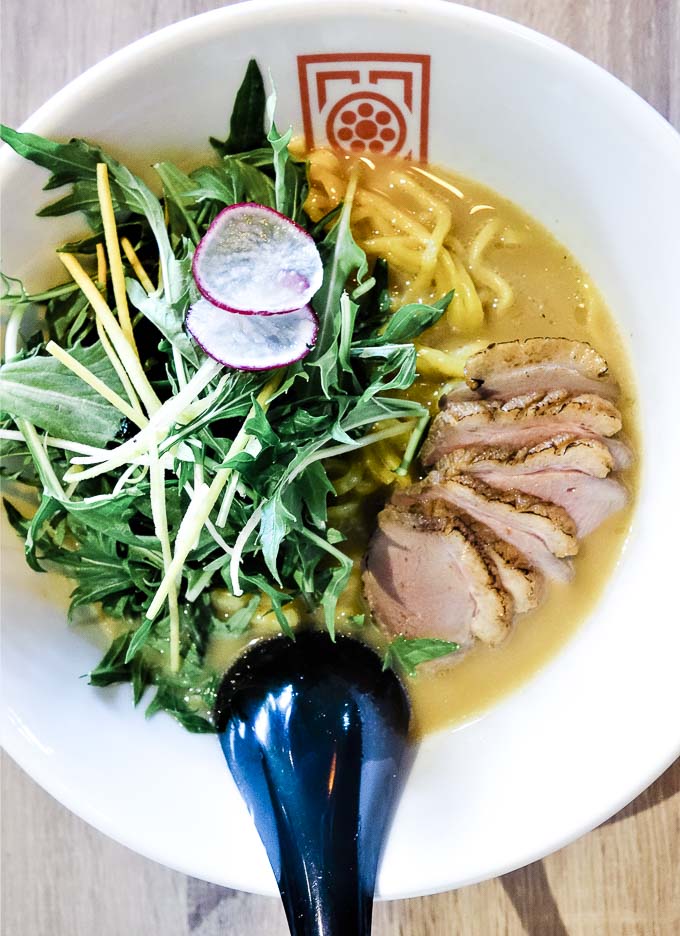 bowl of ramen with pieces of duck and greens