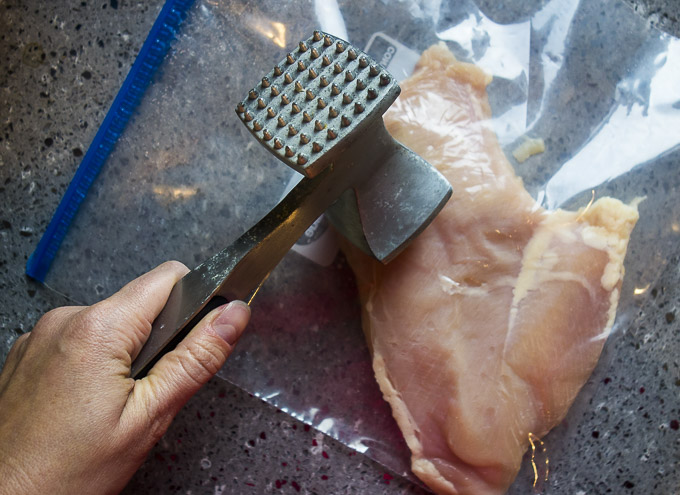 pounding a chicken breast with a mallet