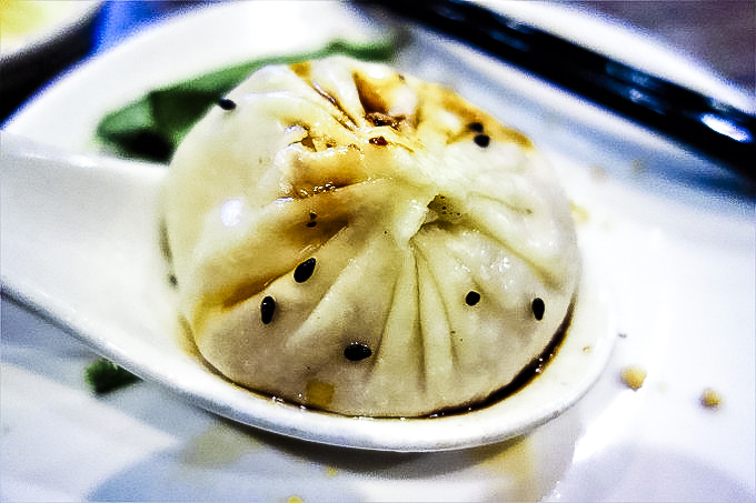 soup spoon holding a dumpling with sesame seeds