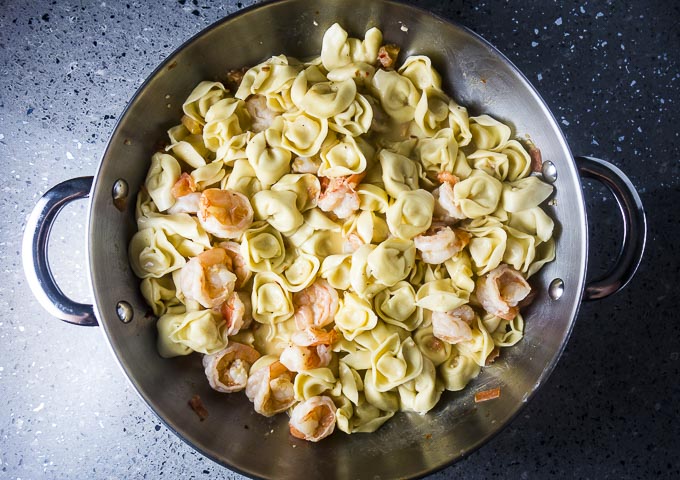 tortellini and cooked shrimp in a skillet