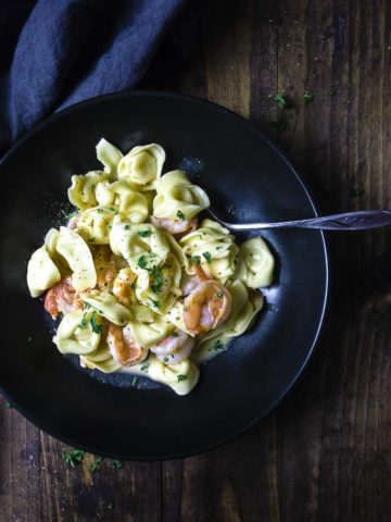 shrimp and tortellini in a bowl with creamy sauce