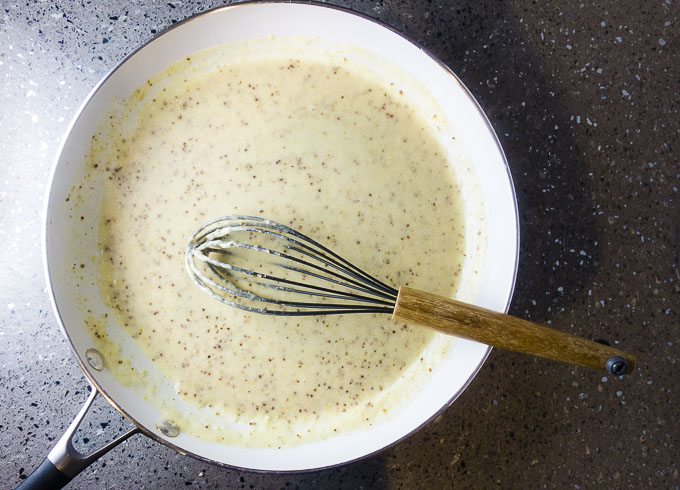 cream sauce in a skillet with a whisk