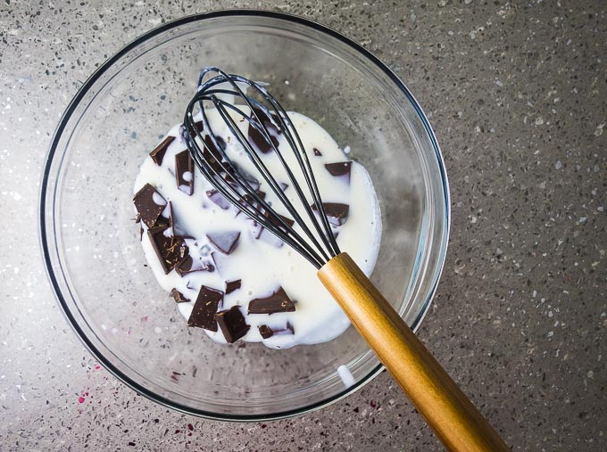 chunks of chocolate and cream in a bowl with a whisk