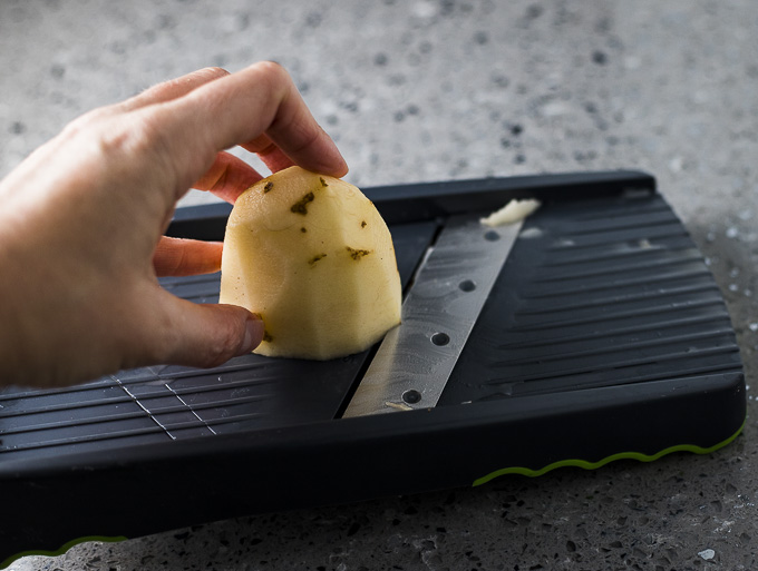 sliding a potato on a mandolin