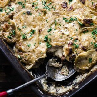 creamy baked scalloped potatoes in a baking dish with a spoon