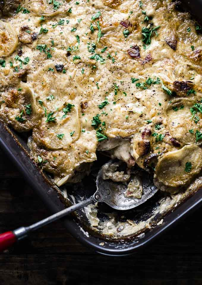 creamy baked scalloped potatoes in a baking dish with a spoon