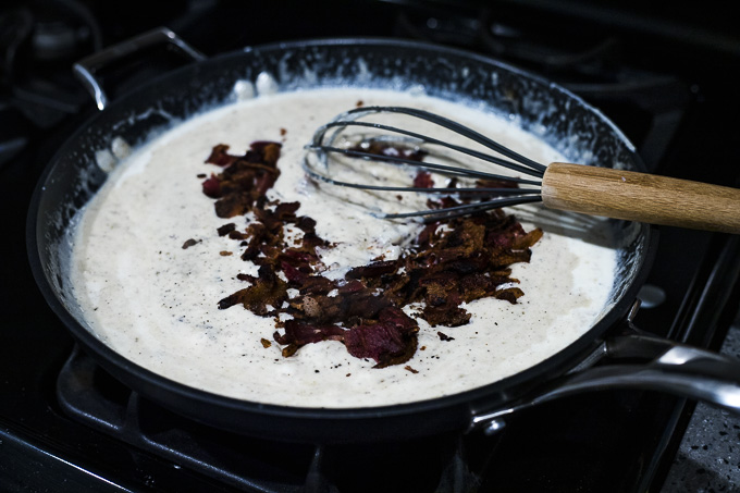bechamel sauce with bacon pieces in a skillet