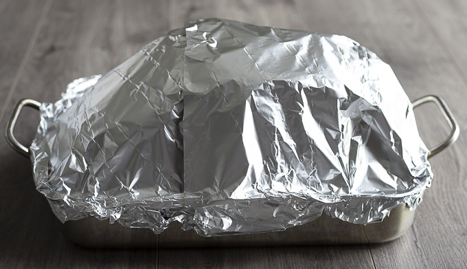 ham covered in foil in a roasting pan