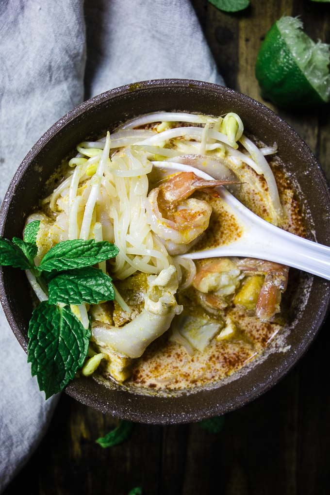 spoon of shrimp in a bowl of creamy coconut soup (laksa)