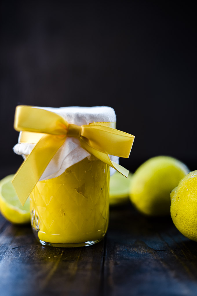 lemon curd in a glass jar with a bow and lemons in the background