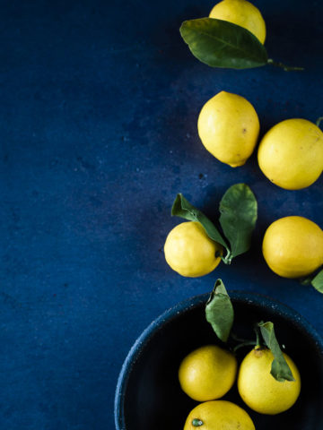 lemons in a bowl and on a surface with leaves on