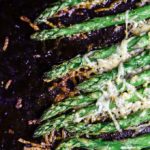 close up of asparagus with crispy browned cheese on top