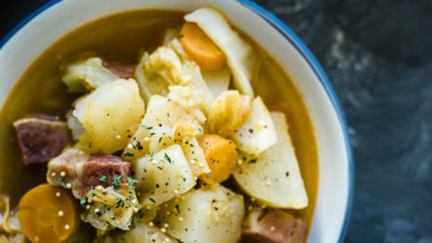 bowl of soup with carrots, potatoes and corned beef garnished with parsley