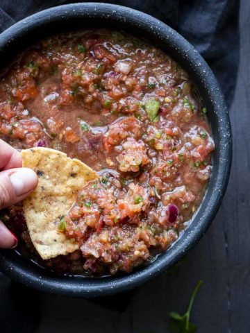 a chip being dipped in a bowl of salsa