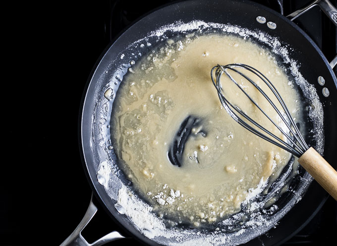 flour and oil being whisked in a skillet