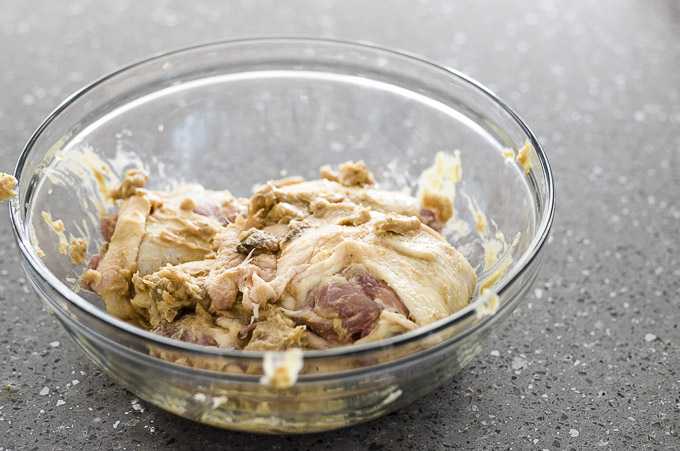 raw chicken coated in brown sauce in a bowl