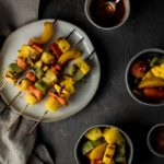 plate of fuirt kebabs with 2 bowls of fruit and chili