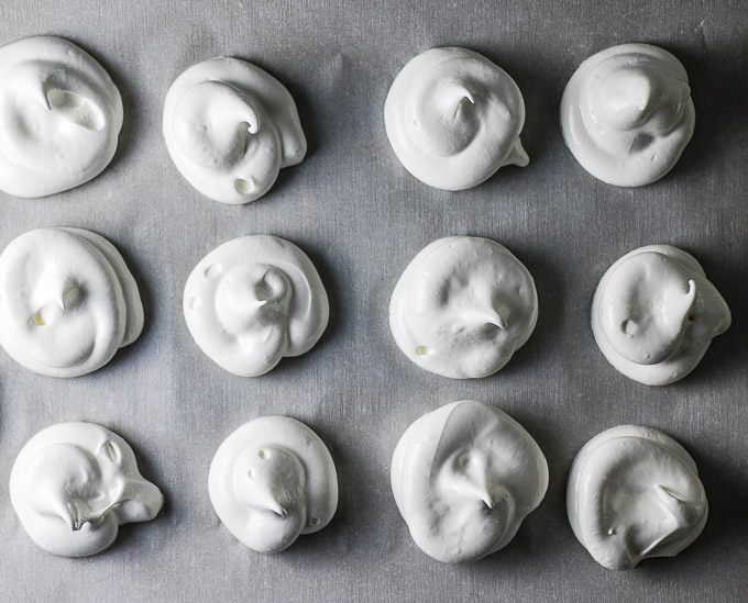 uncooked meringues on a baking tray in circles