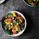 bowl of salad with fruit and spinach in it