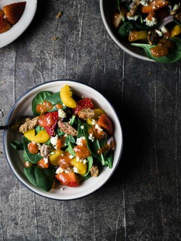 bowl of salad with fruit and spinach in it