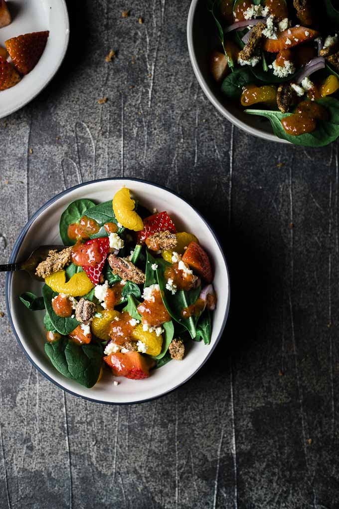 bowl of salad with fruit and spinach in it