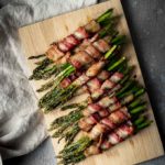 asparagus wrapped in bacon on a board
