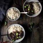 two bowls of beef and rice with chilies on top and side of rice in a bowl