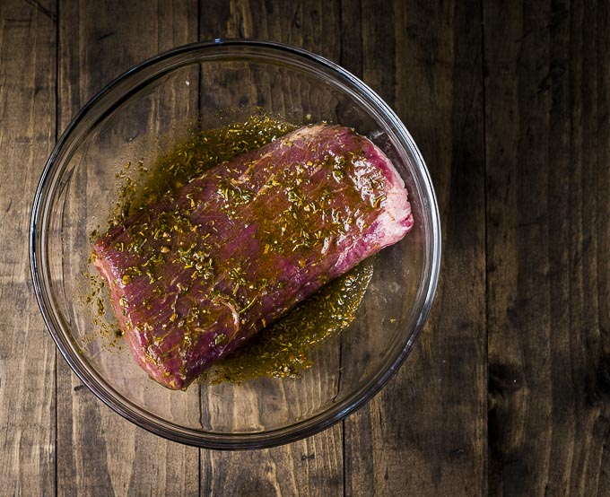 raw flank steak with seasoning in a glass bowl